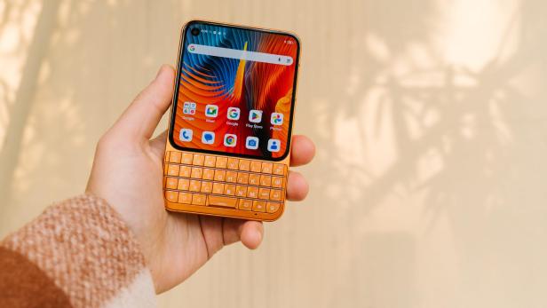Eine Hand hält ein Android-Smartphone mit physischer Tastatur und farbigem Display.
