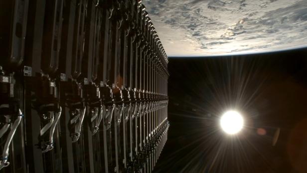 Eine Reihe von Geräten ist vor der Erdkugel und der hellen Sonne im Weltraum zu sehen.