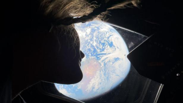 Astronautin Christina Koch blickt aus der Orion-Raumkapsel auf die Erde, aufgenommen mit einem iPhone 17 Pro Max während der Artemis-II-Mission.