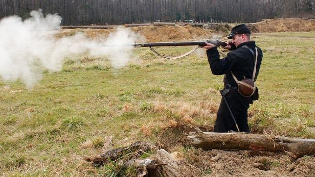 Soldat feuert auf Wiese mit Muskete.