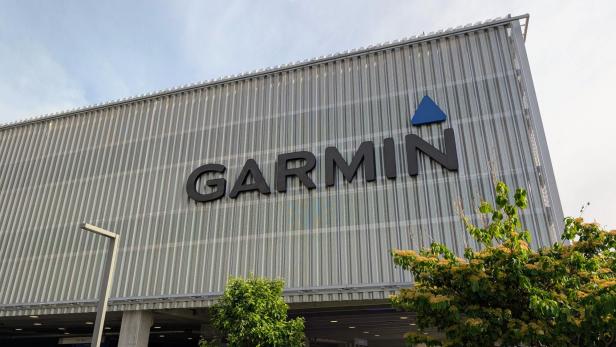 Garmin-Logo an der Fassade eines modernen Gebäudes mit Bäumen im Vordergrund.