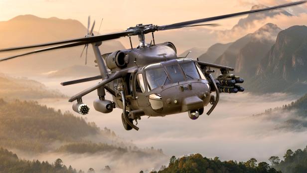 Kampfhubschrauber fliegt vor einer bergigen Landschaft im Nebel