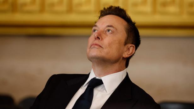 Elon Musk im Anzug blickt nach oben.
