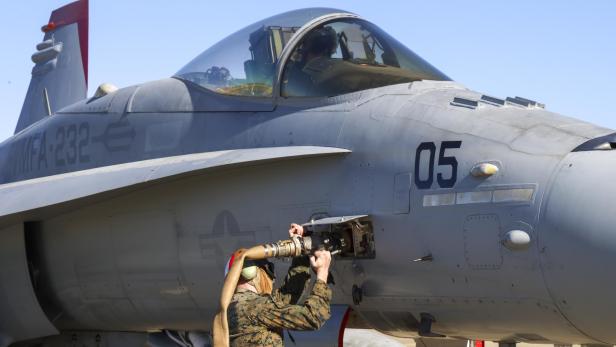 ein grauer Kampfjet steht am Flugfeld und wird betankt