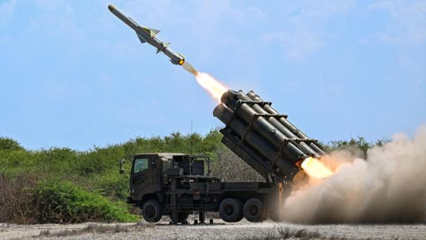Ein Militärfahrzeug feuert eine Rakete in einer staubigen Landschaft bei Tageslicht ab.
