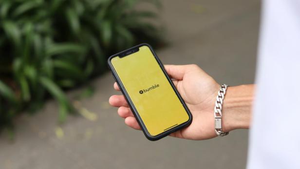 Bumble App auf Handy das in einer Hand liegt