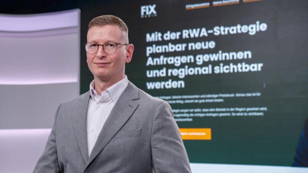 Geschäftsmann im grauen Anzug vor digitaler Präsentationsfläche.