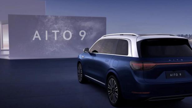 Ein blauer SUV Aito 9 steht vor einer Wand mit großem Aito 9 Schriftzug.