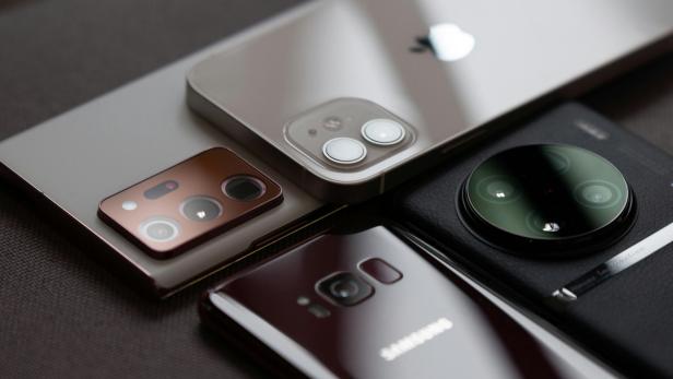 Nahaufnahme von vier Smartphones unterschiedlicher Marken mit Fokus auf die Kameramodule auf der Rückseite.