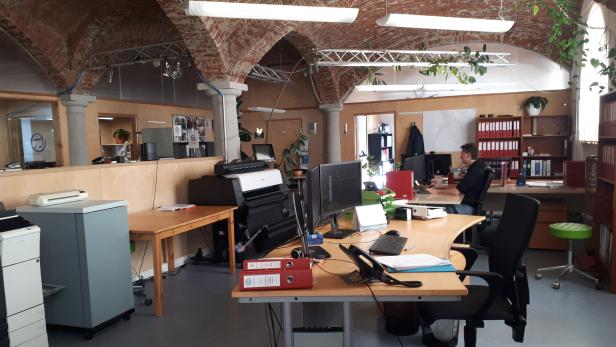 Ein Büro mit mehreren Arbeitsplätzen unter gemauerten Deckenbögen und moderner Büroausstattung.
