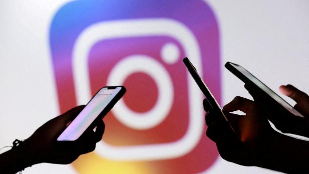 Drei Hände halten Smartphones vor einem großen, unscharfen Instagram-Logo mit Farbverlauf im Hintergrund.