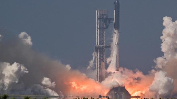 Die SpaceX Starship-Rakete hebt von der Startrampe ab, umgeben von einer riesigen Rauch- und Feuerwolke.
