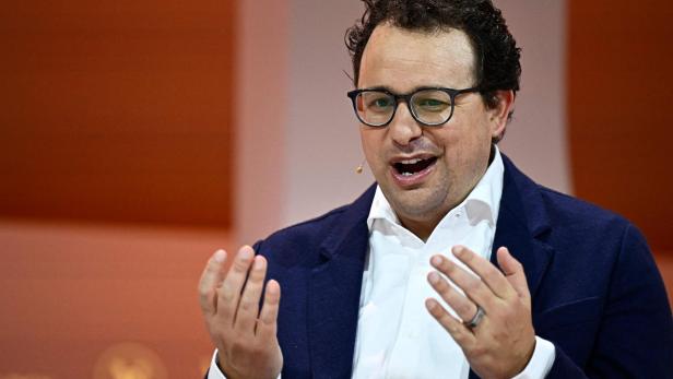 Anthropic-CEO Dario Amodei spricht gestikulierend vor einem orangefarbenen Hintergrund.
