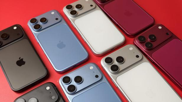 Mehrere iPhone-Dummys in Schwarz, Hellblau, Silber und Dunkelrot auf rotem Untergrund.