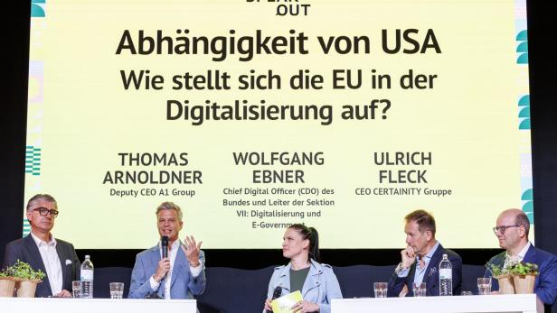 Vier Personen diskutieren auf einer Bühne vor einer großen Tafel mit dem Thema „Abhängigkeit von USA in der Digitalisierung“.