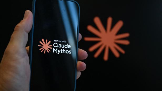 Eine Hand hält ein Smartphone, auf dessen Display das Logo von Anthropic sowie der Schriftzug „Claude Mythos“ vor einem schwarzen Hintergrund zu sehen sind.