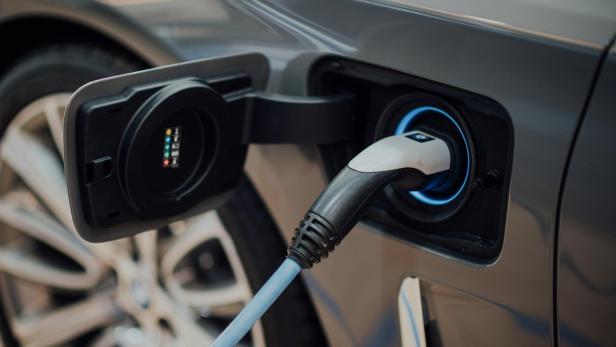 Nahaufnahme eines Elektroautos beim Ladevorgang mit eingestecktem Ladestecker