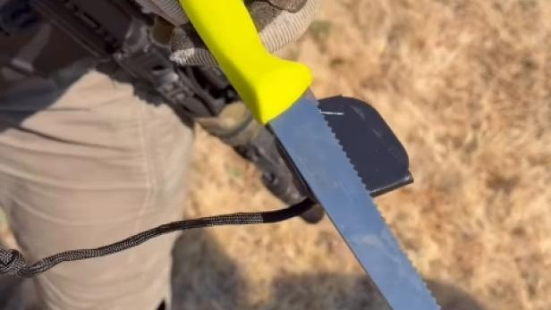 Ausschnitt aus einem Video zeigt einen Polizeibeamten, der ein Messer mit gelbem Griff in der Hand hält, das an einem Magneten hängt