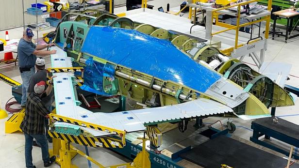 Techniker montieren Tragflächen an den X-65-Rumpf in der Werkhalle.