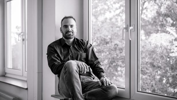 Ein Mann sitzt an einem Fenster; schwarz-weiß-Foto 