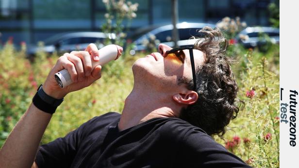 Mann hält einen kleinen Dyson-Handventilator ans Gesicht.