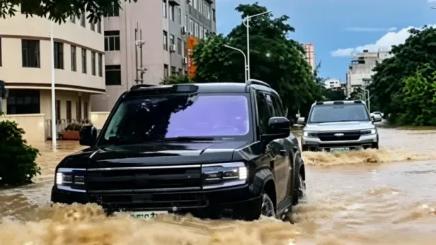 Zwei SUVs fahren durch überflutete Straße.