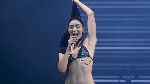 Die Sängerin Lorde singt auf einer Bühne in ein Mikrofon