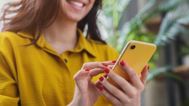 Cropped image of happy girl using smartphone device while chilling at home