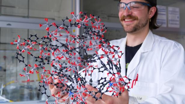 Kalle Mertin, Erstautor der Studie zur Maßstabsvergrößerung der Synthese von CAU-10-H, hält ein Modell einer Metall-organischen Gerüstverbindung (MOF) in den Händen.