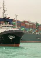 Ein Schlepper namens „Baraka 1“ neben einem großen Containerschiff von Evergreen im Suezkanal.