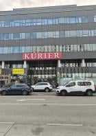 Das Kurier-Gebäude in Wien mit geparkten Autos davor.