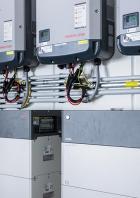 Mehrere Fronius Symo Wechselrichter und BYD Batteriespeicher sind an einer Wand montiert.