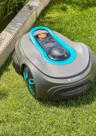 Ein grauer Gardena Mähroboter steht auf einem grünen Rasen.