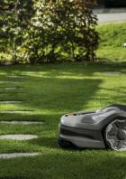 Ein Rasenmähroboter steht auf einem grünen Rasen mit Trittsteinen.