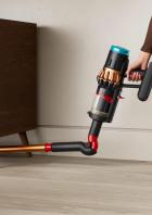 Ein Dyson V16 Staubsauger wird unter einem Holzschrank verwendet.