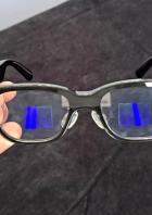 Eine Hand hält die Rokid-Brille mit blauen Anzeigen in den Gläsern.