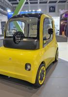 Ein gelbes elektrisches Microcar von Astraux steht auf einer Messe.