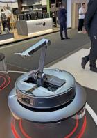 Ein Roborock Saugroboter Saros Z70 mit ausfahrbarem Arm auf einem Messestand.