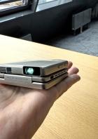 Ein Mini-Projektor liegt in einer Hand.