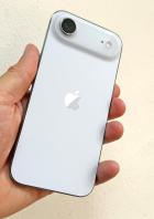 Ein weißes iPhone mit einem ungewöhnlichen Kamera-Aufsatz wird in der Hand gehalten.