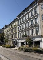 Straßenansicht mit Wohnhäusern und Straßenbahnschienen in Wien.