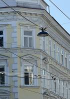 Ein gelbes Gebäude mit weißen Fensterrahmen und verzierten Fassaden unter einem blauen Himmel.