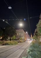 Eine Straßenbahnhaltestelle in einer Stadt bei Nacht, aufgenommen im Nachtmodus.