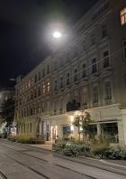 Eine abendliche Straßenszene in Wien mit Straßenbahnschienen und beleuchteten Gebäuden.