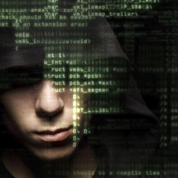 Ein Mann mit Kapuze vor einem Hintergrund aus Computercode.