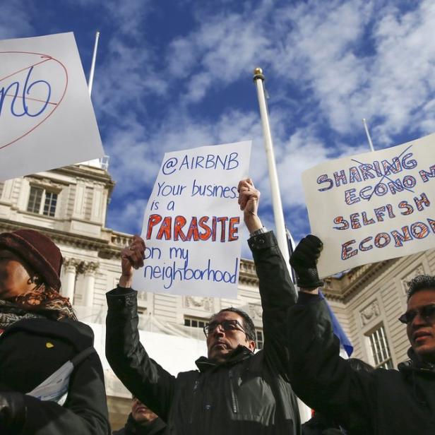 Menschen demonstrieren mit Schildern gegen Airbnb.