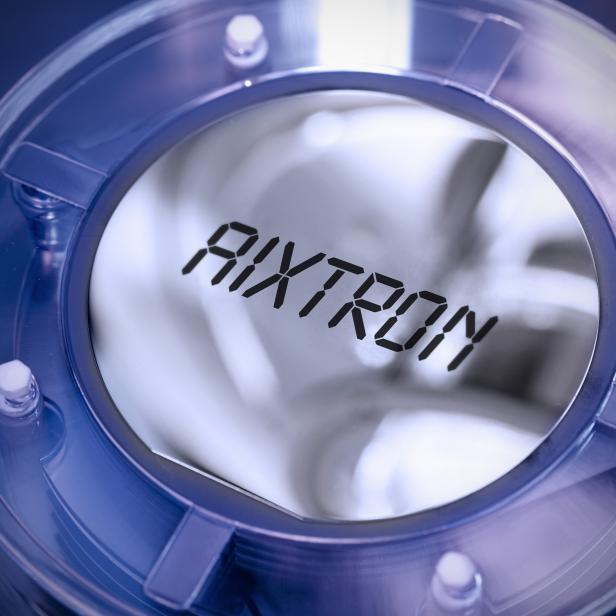 Das Logo von AIXTRON ist in einem runden, transparenten Gehäuse zu sehen.