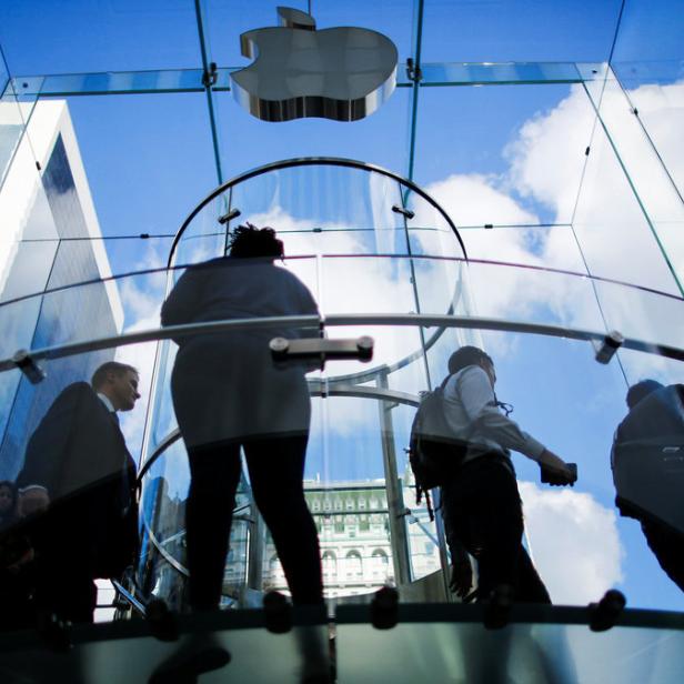Menschen betreten einen Apple Store mit einem gläsernen Eingangsbereich.