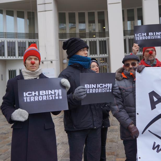 Menschen mit roten Nasen demonstrieren mit Schildern, auf denen „Ich bin Terrorist“ steht.