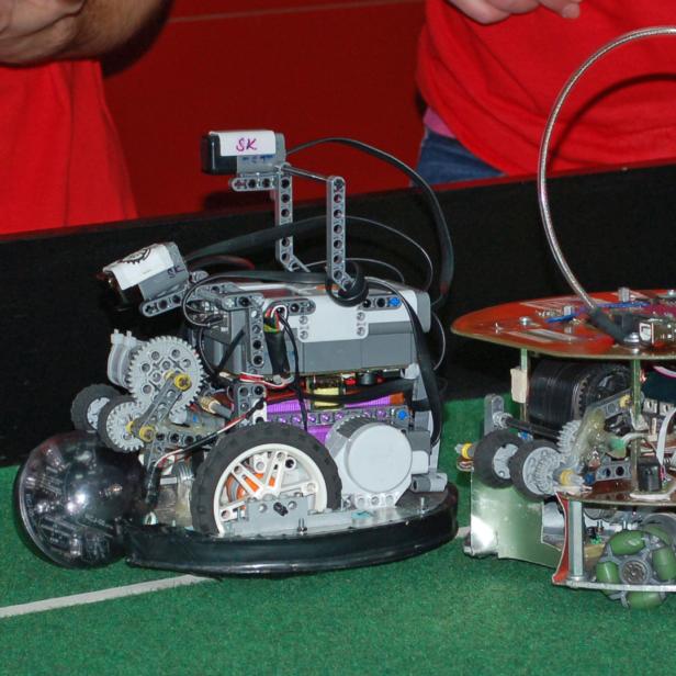 Zwei selbstgebaute Roboter stehen auf einem grünen Untergrund.